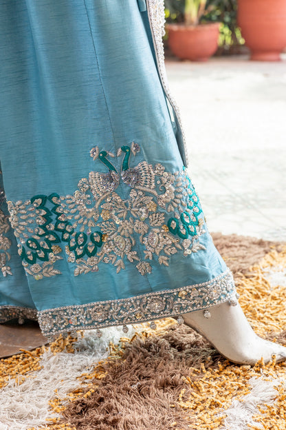 Teal Pakistani formal suit by MariamRaj featuring hand-embellished net shirt with zari, mirror work, pearls, and sequins, paired with tissue inner, embroidered pants, and a net dupatta.