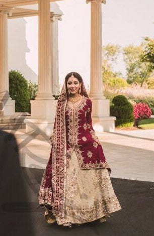 Deep red Pakistani bridal lehenga by MariamRaj with maroon embroidered hi-low shirt, golden banarsi chiffon lehenga, and embroidered dupatta – ideal for weddings and baraat events.
