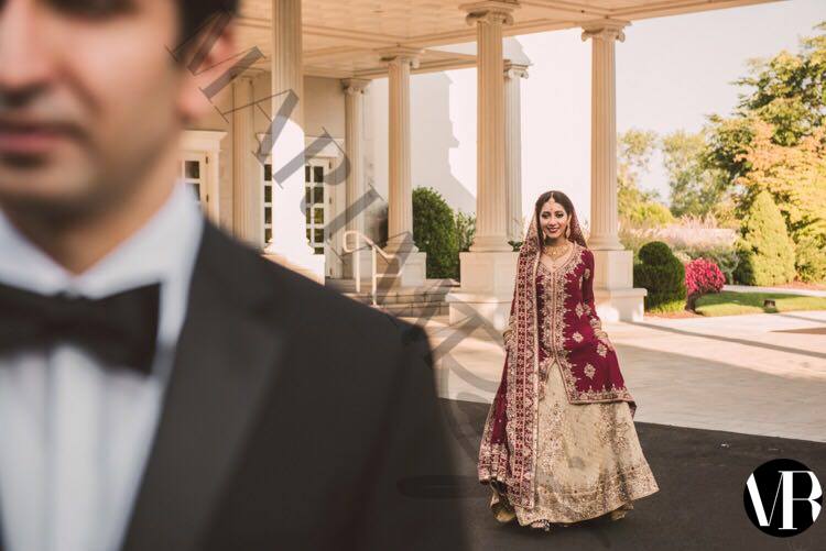 Deep red Pakistani bridal lehenga by MariamRaj with maroon embroidered hi-low shirt, golden banarsi chiffon lehenga, and embroidered dupatta – ideal for weddings and baraat events.