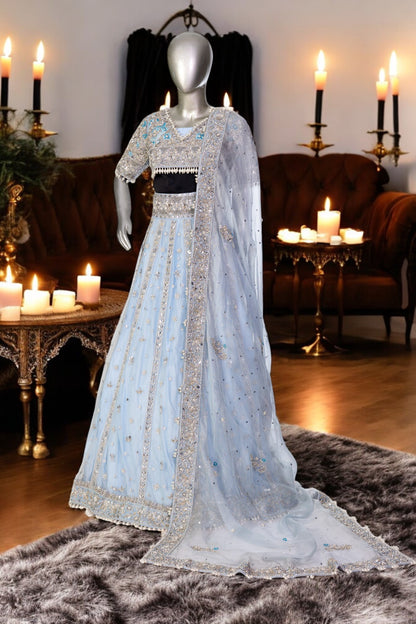 Elsa – Ice blue Pakistani bridal lehenga by MariamRaj featuring a hand-embroidered raw silk blouse with tassels, net lehenga with intricate motifs, and a fully embellished net organza dupatta. Custom stitched for Pakistani brides in USA and UK.