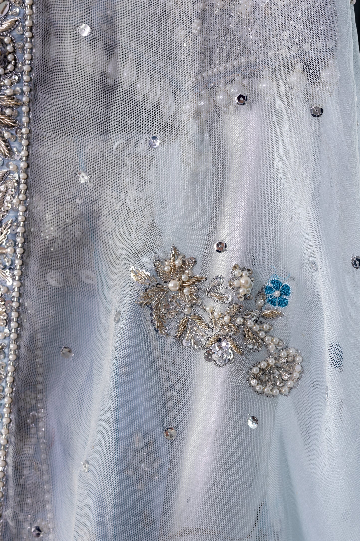 Elsa – Ice blue Pakistani bridal lehenga by MariamRaj featuring a hand-embroidered raw silk blouse with tassels, net lehenga with intricate motifs, and a fully embellished net organza dupatta. Custom stitched for Pakistani brides in USA and UK.
