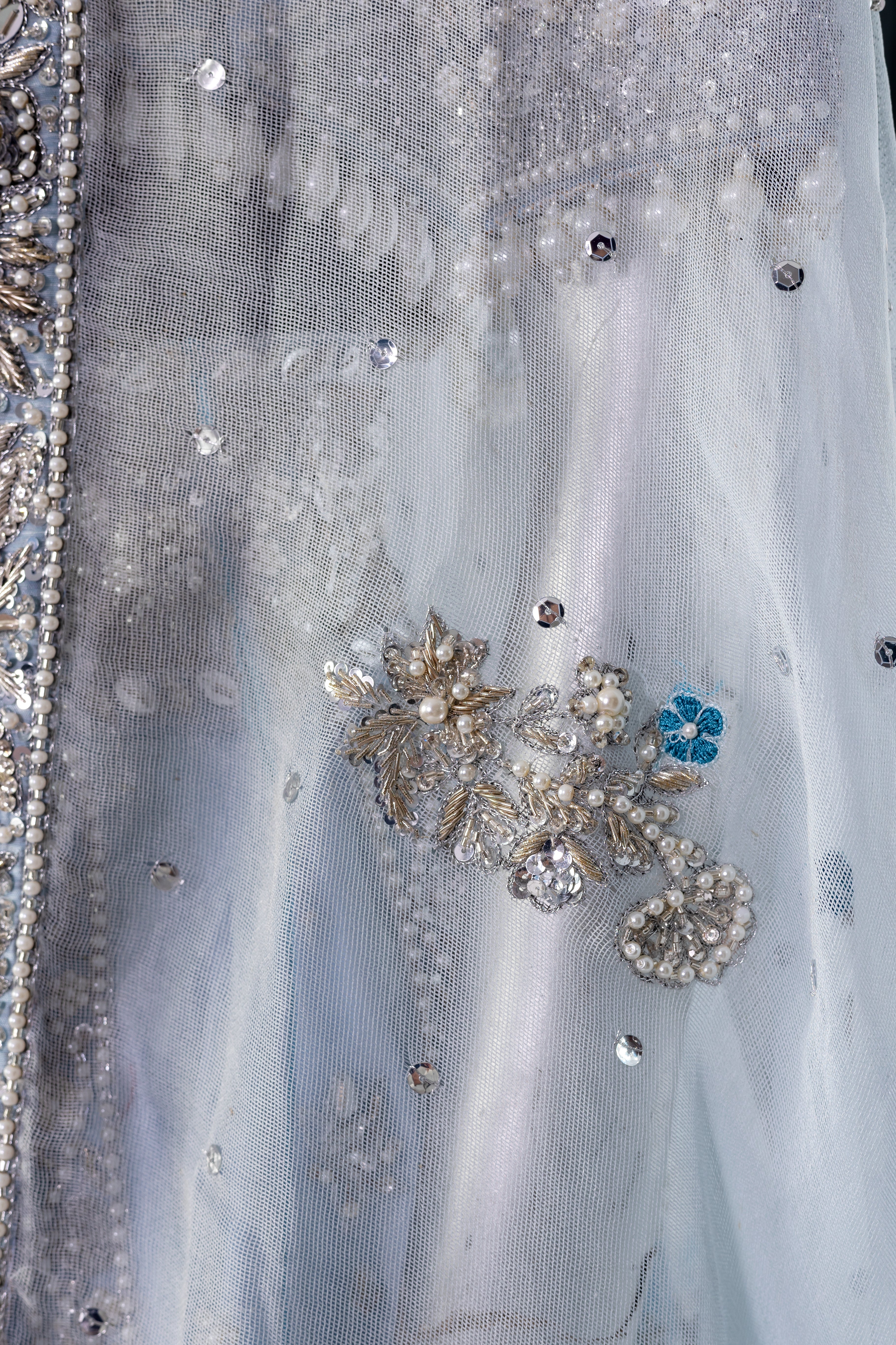 Elsa – Ice blue Pakistani bridal lehenga by MariamRaj featuring a hand-embroidered raw silk blouse with tassels, net lehenga with intricate motifs, and a fully embellished net organza dupatta. Custom stitched for Pakistani brides in USA and UK.