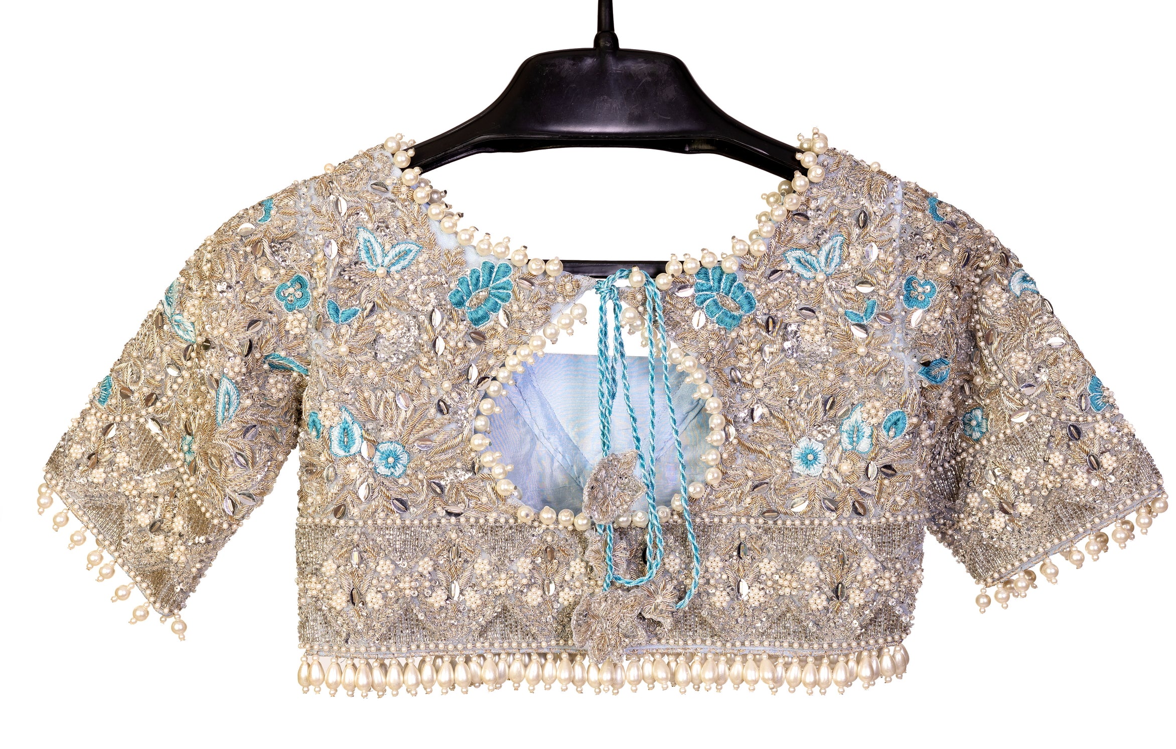 Elsa – Ice blue Pakistani bridal lehenga by MariamRaj featuring a hand-embroidered raw silk blouse with tassels, net lehenga with intricate motifs, and a fully embellished net organza dupatta. Custom stitched for Pakistani brides in USA and UK.