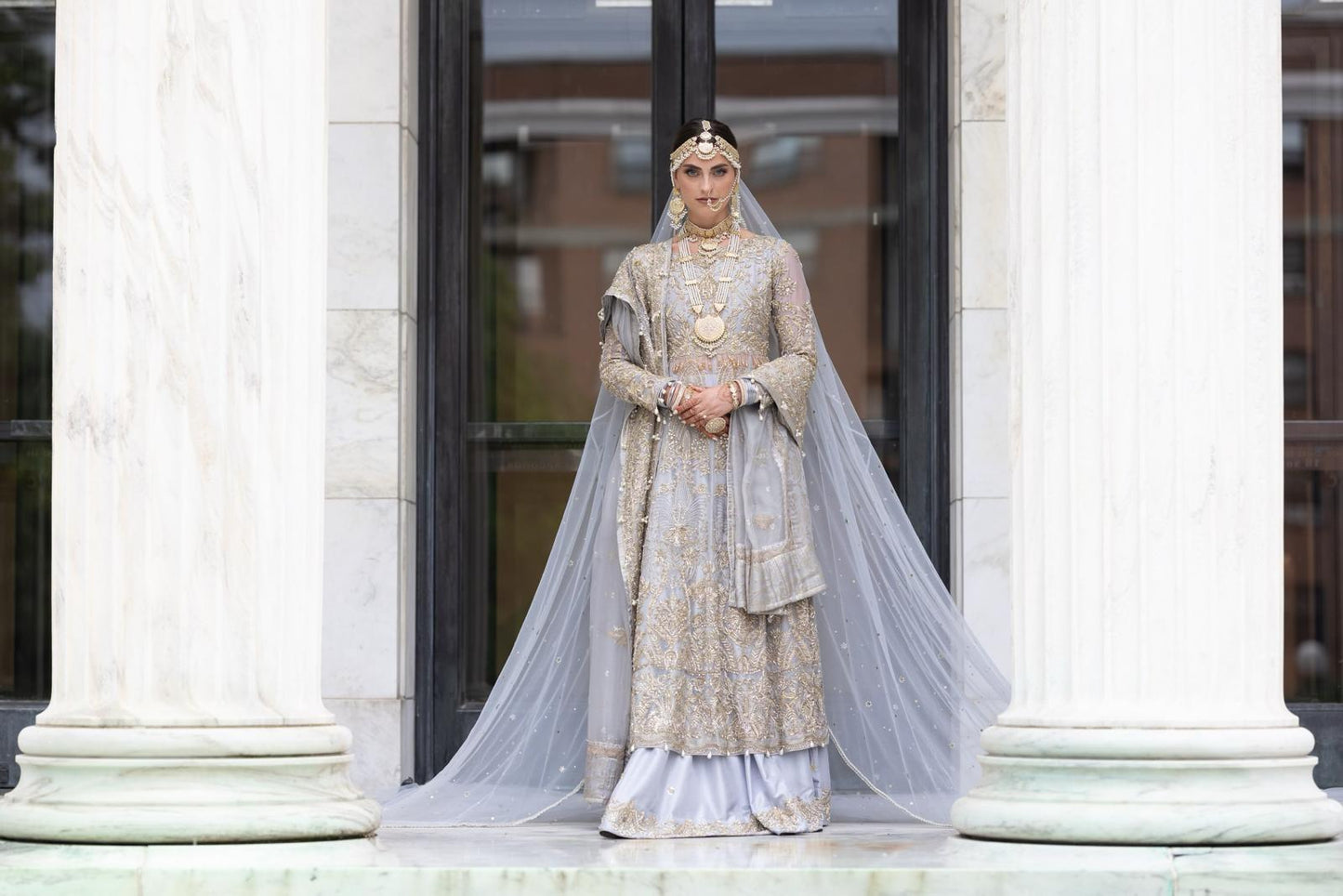 Ice Blue Pakistani bridal dress by MariamRaj featuring raw silk anarkali frock with golden embroidery, paired with embroidered sharara and net dupatta – custom stitched for overseas brides.