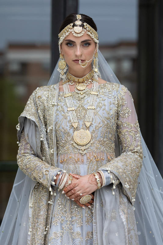 Ice Blue Pakistani bridal dress by MariamRaj featuring raw silk anarkali frock with golden embroidery, paired with embroidered sharara and net dupatta – custom stitched for overseas brides.