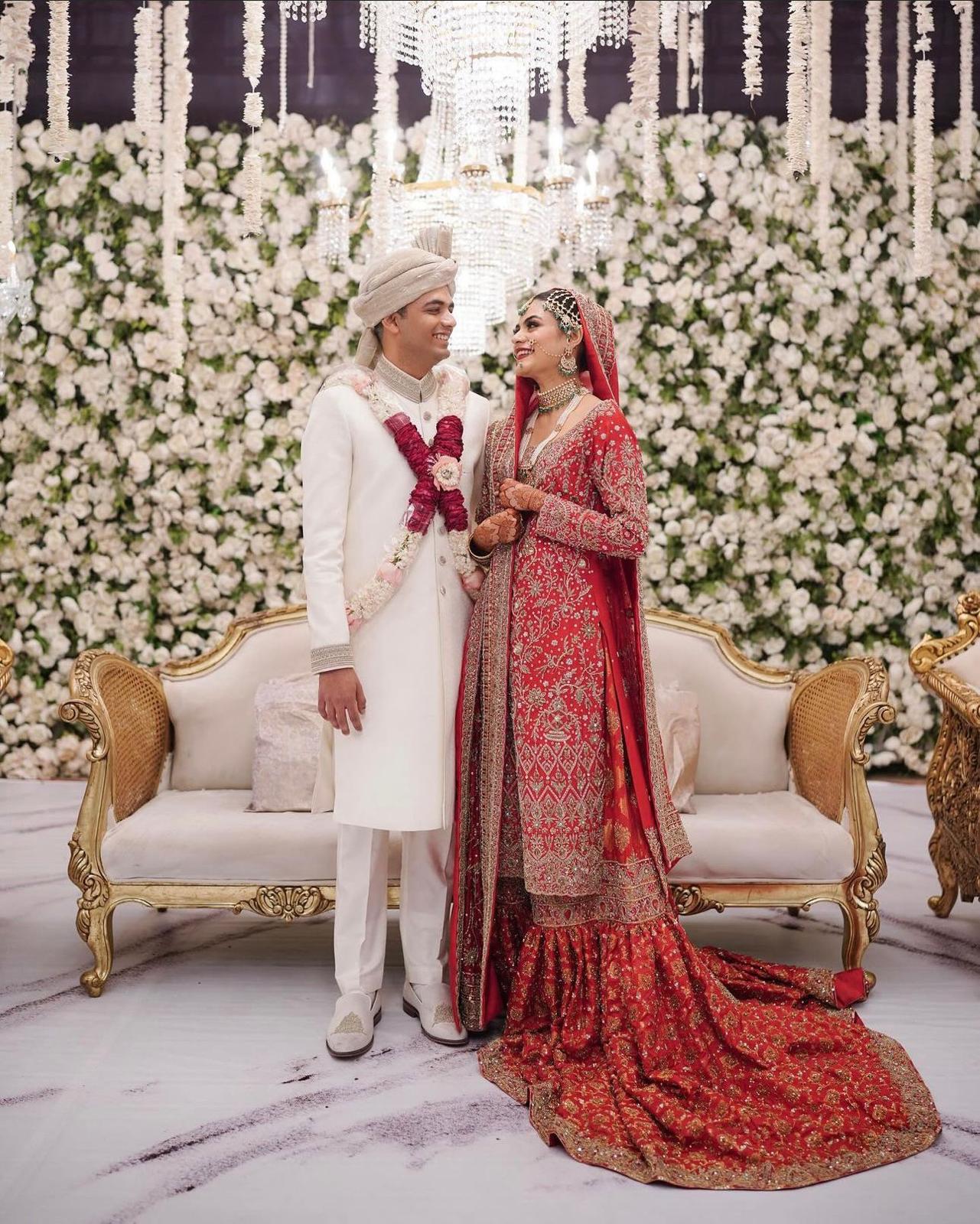 Red bridal farshi gharara by MariamRaj featuring embroidered raw silk kameez, brocade silk gharara, and embellished khaadi silk dupatta – ideal for baraat and Pakistani weddings.