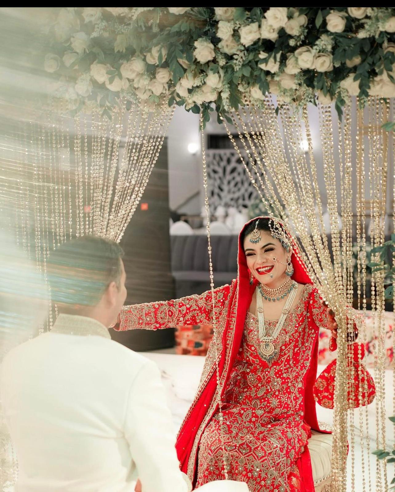 Red bridal farshi gharara by MariamRaj featuring embroidered raw silk kameez, brocade silk gharara, and embellished khaadi silk dupatta – ideal for baraat and Pakistani weddings.